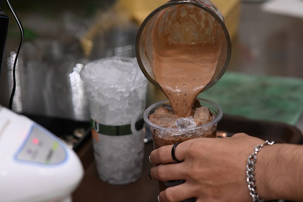 Vaso alto de batido de chocolate y plátano con cacao espolvoreado