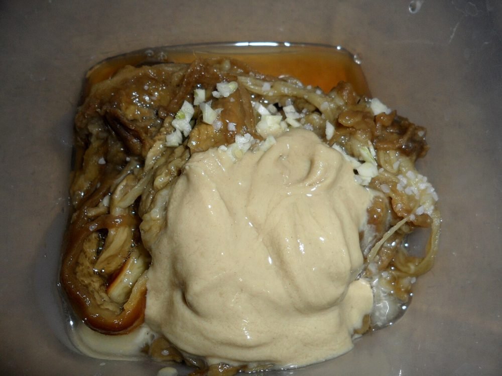 Mitades de berenjena asada con salsa de tahini y granada por encima