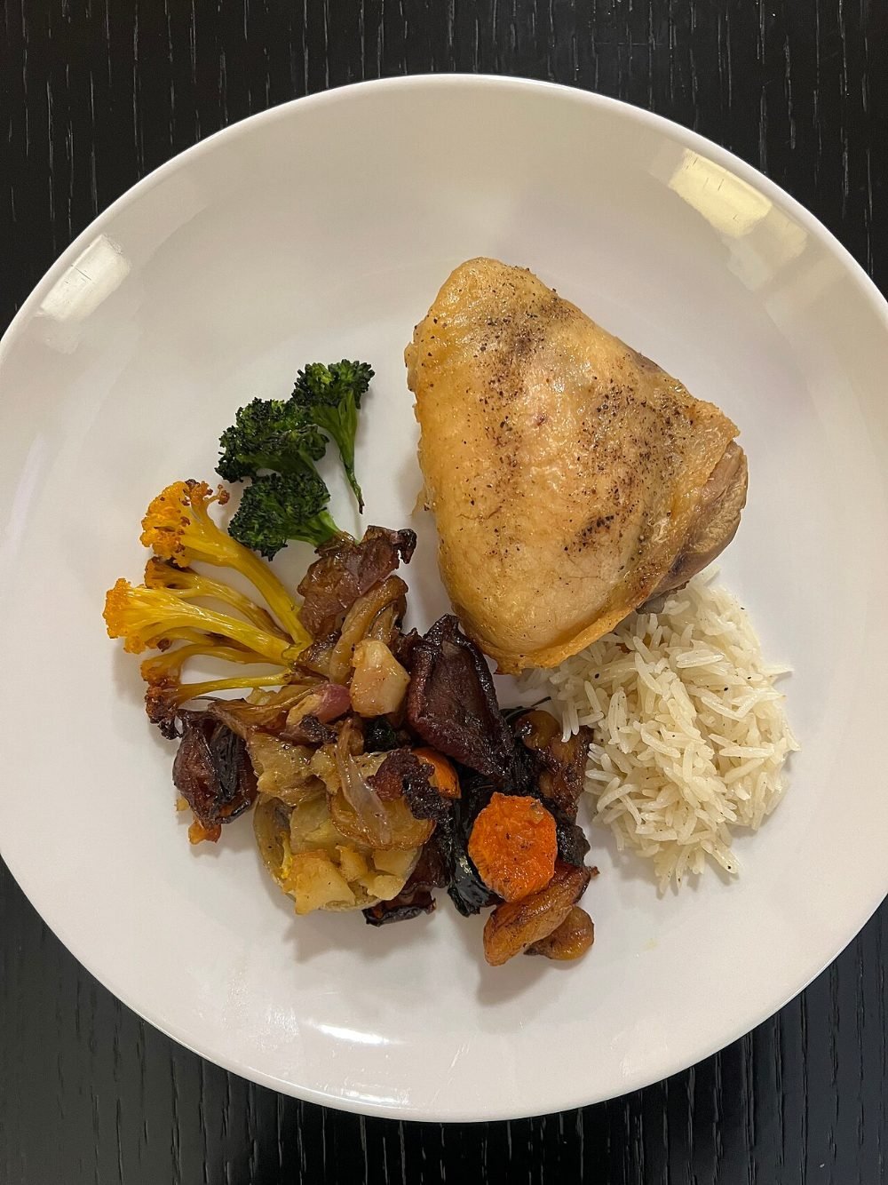 Bandeja de horno con contramuslos de pollo dorados sobre zanahorias y cebolla