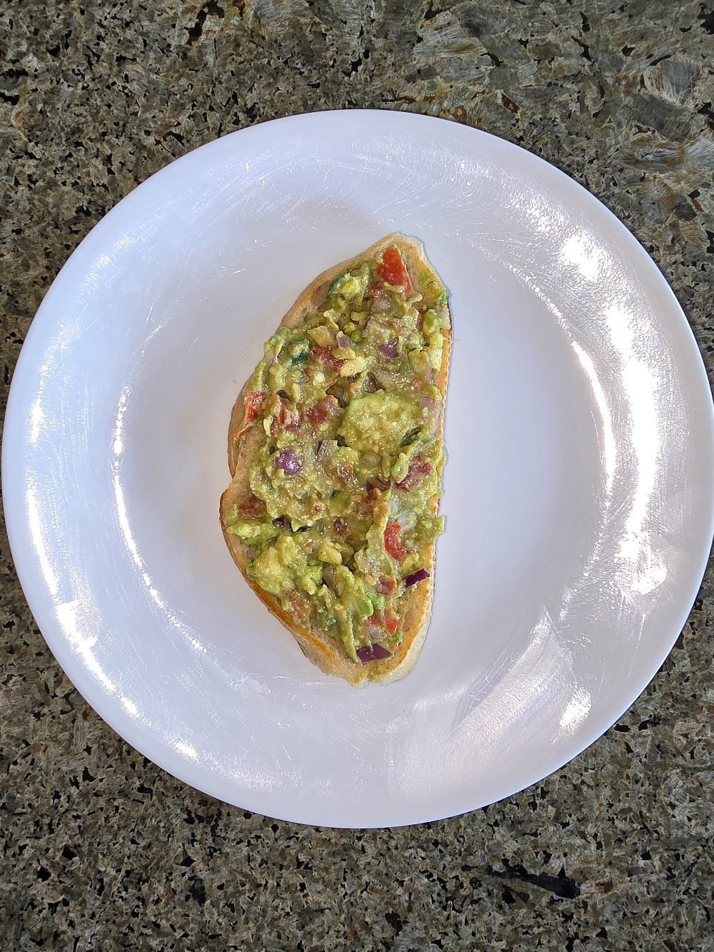 Tostada de pan integral con aguacate machacado y huevo escalfado encima